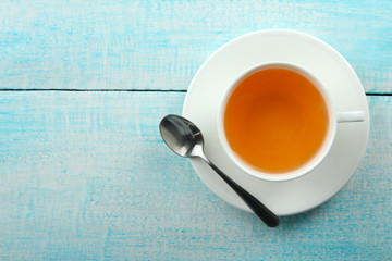 a Cup of fragrant green tea and an iron spoon on wooden background