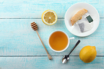 a Cup of fragrant green tea and lemon with a wooden spoon for honey on a wooden background