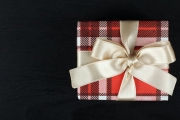 beautiful gift wrapped with festive ribbon on a black wooden background