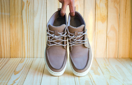gray suede shoes holding by hand on wooden background