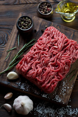 Raw fresh ground beef meat and seasonings, rustic wooden setting