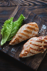 Rustic wooden serving board with grilled chicken breast filet