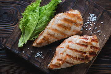 Top view of grilled chicken breasts and green salad, close-up