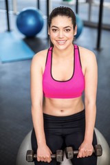 Smiling fit woman lifting dumbbells