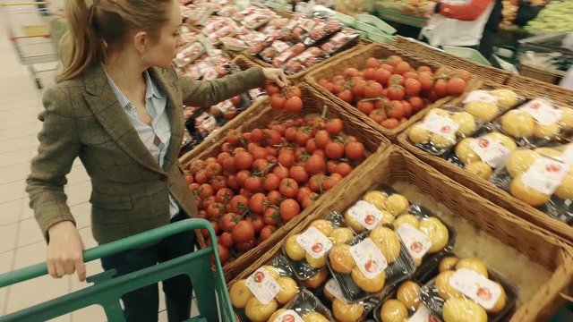 Woman selecting frash tomatoes in modern supermarket