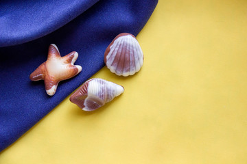 Seashells chocolates on a blue and yellow fabric.