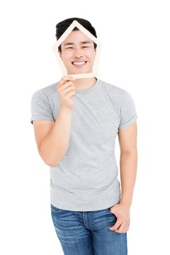 Young man holding house shaped popsicle sticks on face
