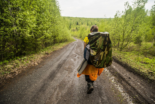 Caucasian backpacker walking on rural dirt road