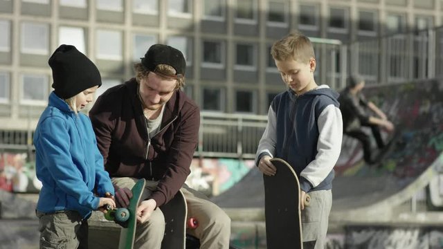Two young boys and one adult reparing skateboard