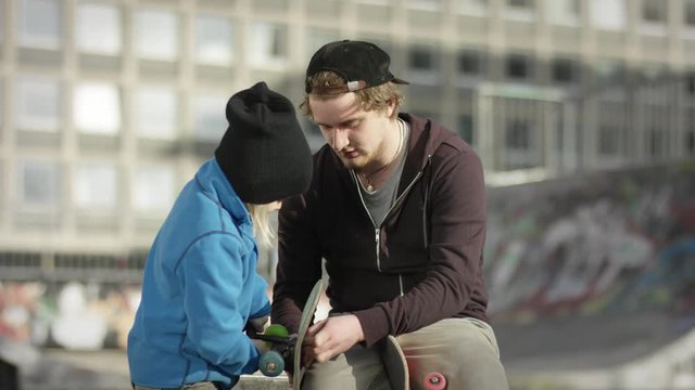 Skater reparing skateboard with his father