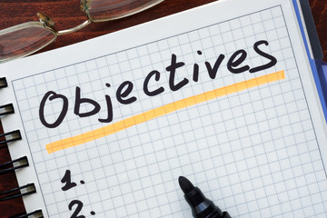 Objectives concept  written in a notebook on a wooden table.