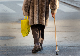 Frau mit Einkaufstasche und Gehstock