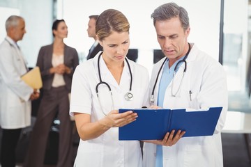 Two doctors looking at clipboard and discussing