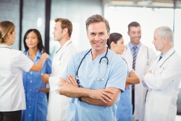 Happy male doctor standing with arms crossed