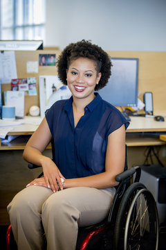 Mixed race businesswoman in wheelchair at office desk