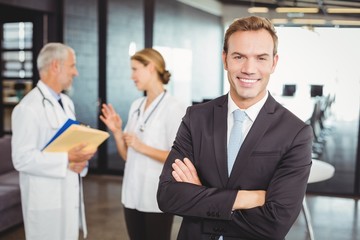 Portrait of happy doctor standing with arms crossed