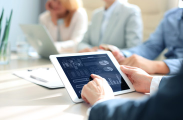 Cropped shot of a group of businesspeople looking at graphs on digital tablets