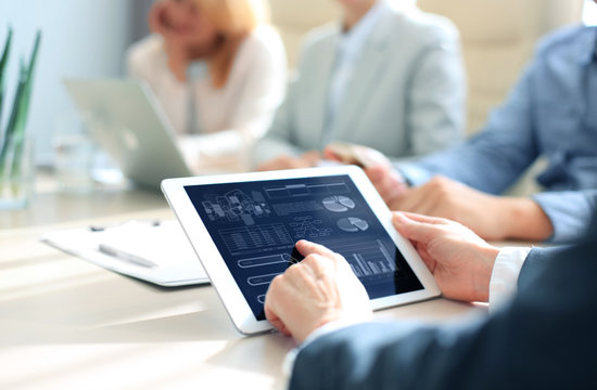 Cropped shot of a group of businesspeople looking at graphs on digital tablets