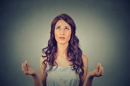 young woman meditating looking up isolated on gray wall background