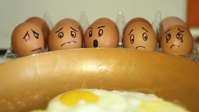 eggs with painted faces look on the pan ,scrambled eggs with humor.