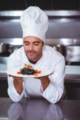 Male chef with eyes closed smelling food in commercial kitchen