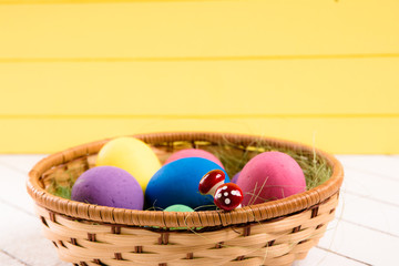 Colorful Easter eggs in basket on a wooden background. Eco-friendly material without violence against animals