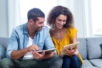 Young couple using a digital tablet on sofa