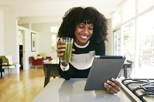 Mixed race woman using digital tablet in domestic kitchen