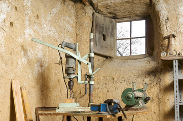 DIY workshop ,wooden workbench,  of handyman with vice,drill and grinder  in old  mud house