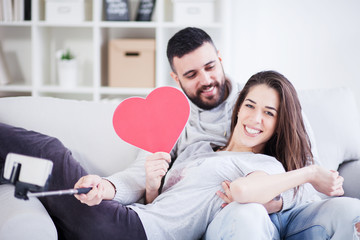 Valentines couple taking selfie and sharing cardboard heart and love,small depth of field