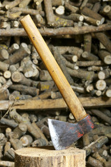 old axe , hatchet , in stump with unfocused  firewood background