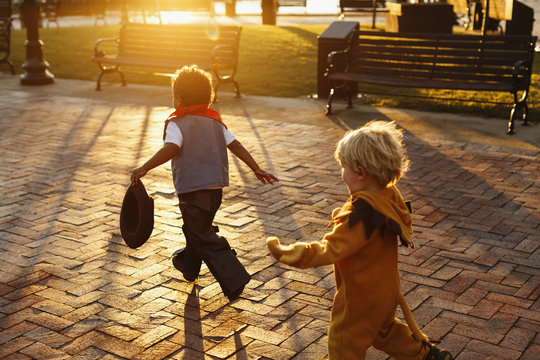 Boys playing in costumes on the sidewalk