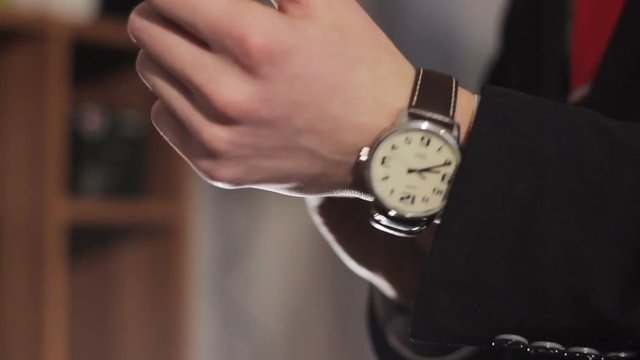Male businessman puts his hand on the clock