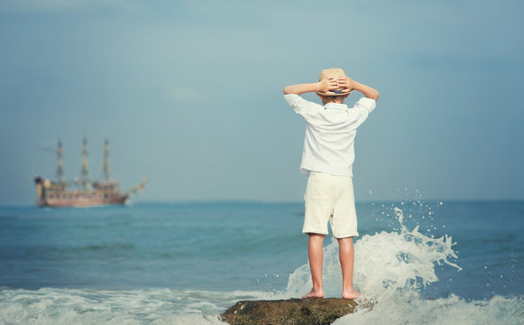 Boy looking on big old ship on the sea