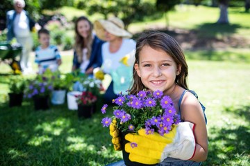 Girl holding a flower pot while gardening with family