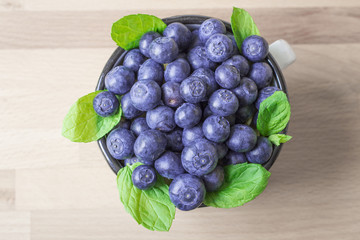 Upper view on blueberries with leaves of mint on wood