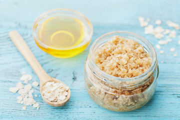 Body scrub of oatmeal, sugar, honey and oil in glass jar on blue rustic table, homemade cosmetic...