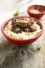 Fried beef with noodles and sesame seeds