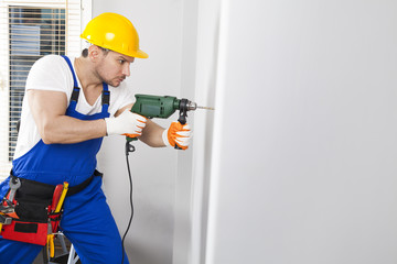 Young man drilling hole in wall