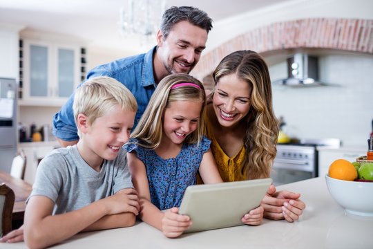 Parents and kids using digital tablet in kitchen