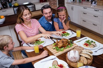 Woman cutting roasted turkey while having meal with his family