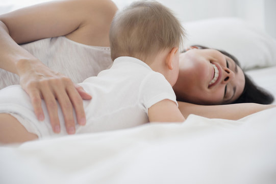 Mixed race mother playing with baby on bed