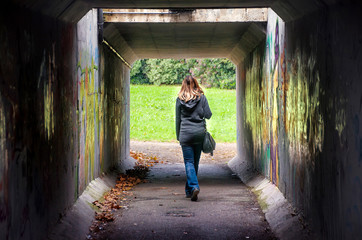woman walk alone tunnel dark underpass  - obrazy, fototapety, plakaty