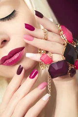 Fotobehang Разноцветный бордовый маникюр крупным планом на ногтях и макияж на девушке. © marigo