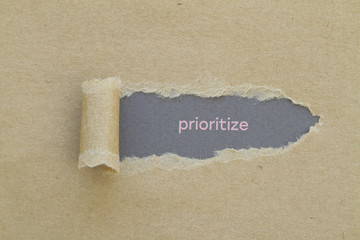 Prioritize word written under torn paper.