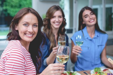Friends holding glass of wine at home
