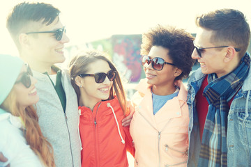 happy teenage friends in shades talking on street