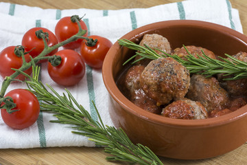 Small croquettes with rosemary and cherry on kitchen towel in clay bowl