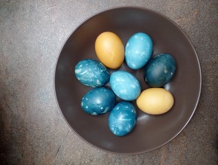 Blue and yellow easter eggs in brown plate