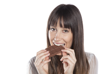Woman eating chocolate. Beautiful girl biting a chocolate bar. Isolated on white background.
